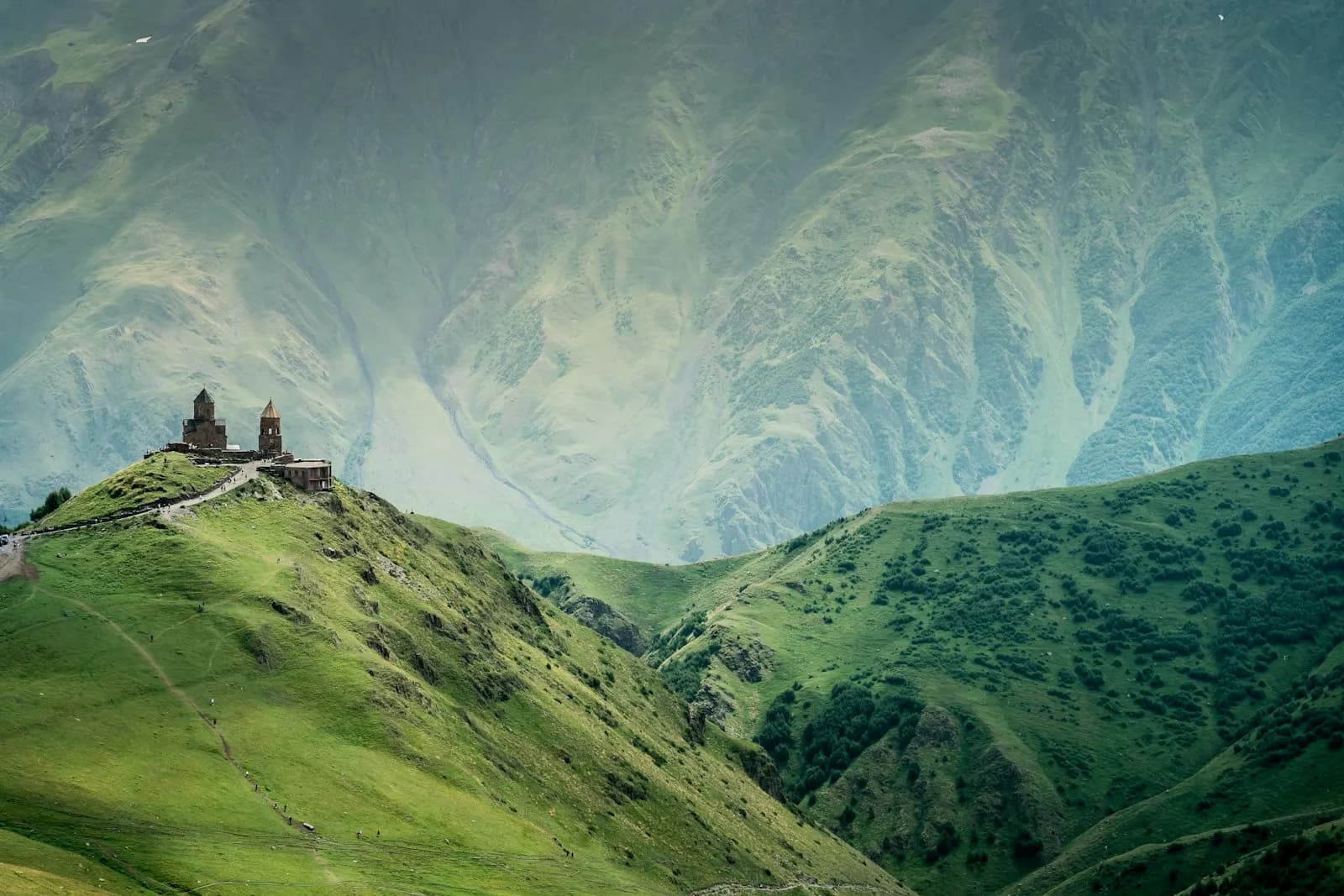 Gergeti Trinity Church on a green ridge below the Caucasus mountains