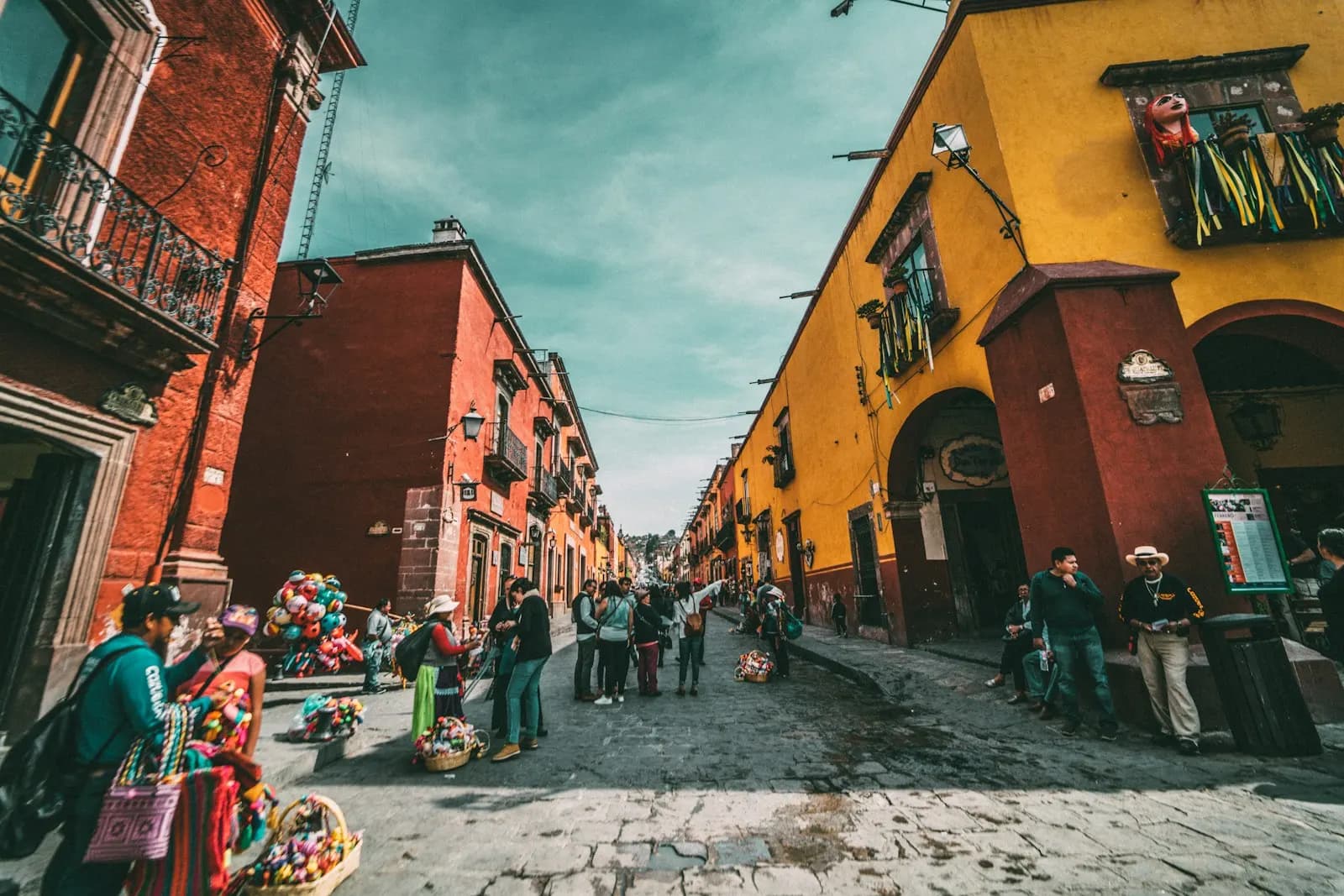 A colourful colonial street in Mexico with market stalls and people walking
