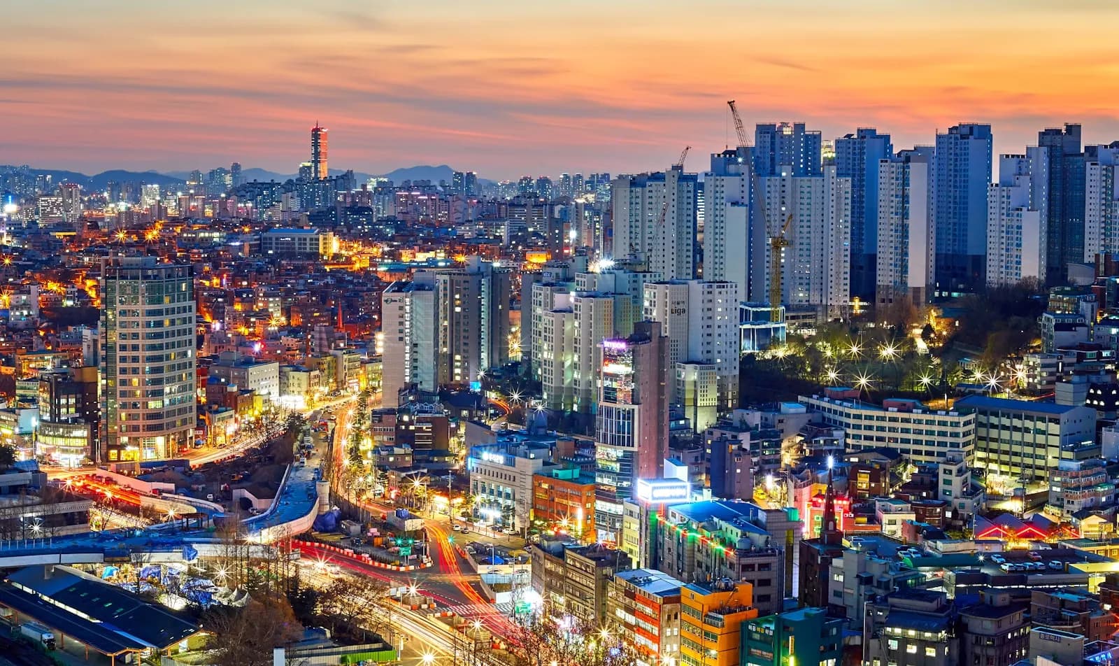 The Seoul skyline at dusk, neon and traffic under an orange sky